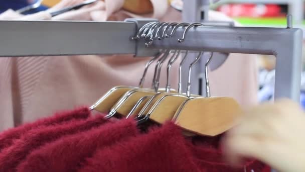 妇女选择柔和温暖舒适的毛衣在衣架上 — 图库视频影像