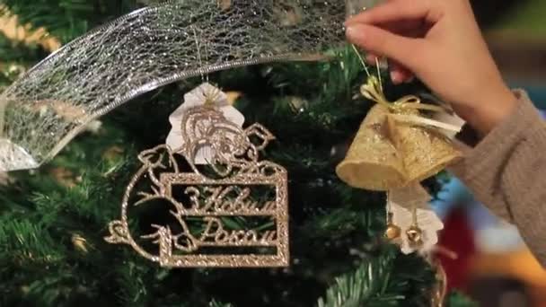 Año Nuevo. La mano femenina pone juguetes en el árbol de Navidad . — Vídeos de Stock