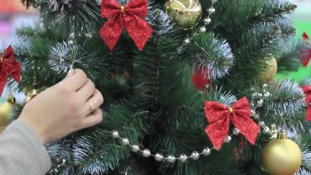 Nieuwjaar. Vrouwelijke hand zet speelgoed op de kerstboom. — Stockvideo