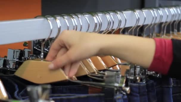 Mains féminines sur le toucher un cintre avec des vêtements en boutique . — Video