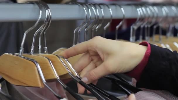 Woman choosing pastel warm cozy sweaters on hangers — Stock Video