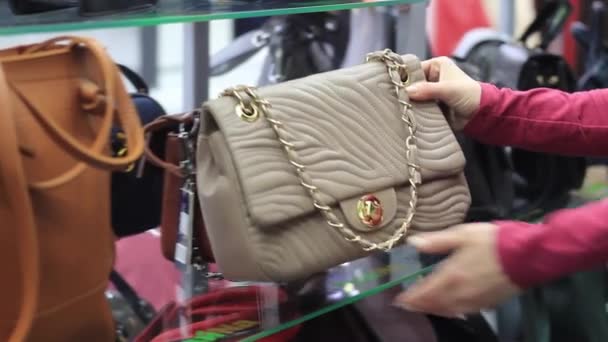 Γυναικεία χέρια επιλέγει μια γυναικεία τσάντα στο κατάστημα — Αρχείο Βίντεο