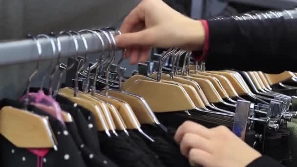 Las manos femeninas tocan una percha con ropa en boutique . — Vídeo de stock