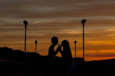 Gün batımında sevgi dolu bir çiftin siluetleri.