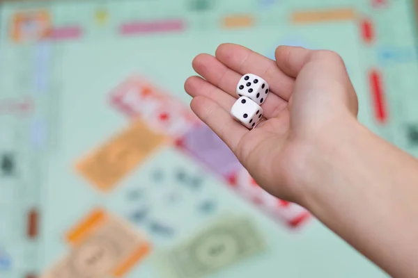 female hand throws dice in a board game close up