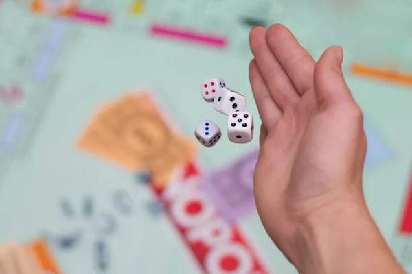 Mão feminina joga dados em um jogo de tabuleiro de perto — Fotografia de Stock