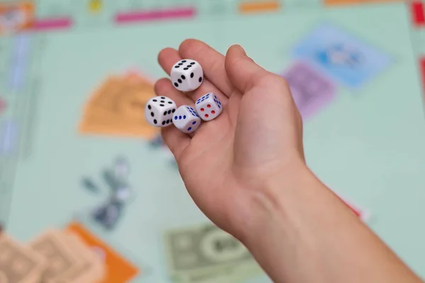 female hand throws dice in a board game close up