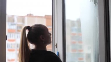 Kız daire bir pencerede yıkar.