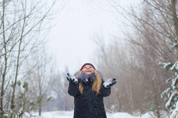 Девушка радуется и бросает снег в зимний сезон — стоковое фото