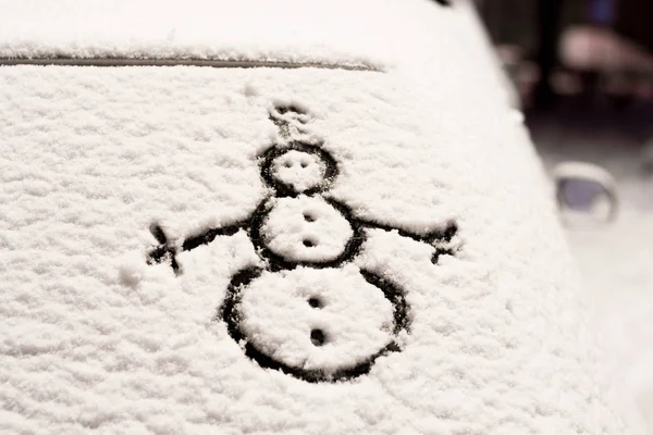 snowman drawing on snowy car window close up