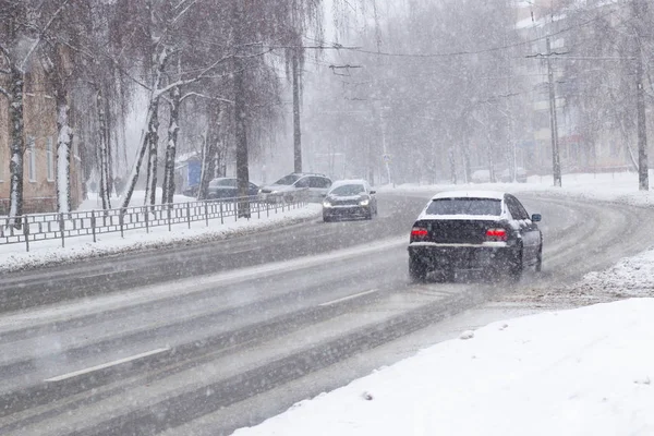 Samochody na zaśnieżonej drodze, na których spadnie śnieg. — Zdjęcie stockowe