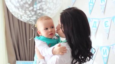 Anne küçük oğlu onun kollarında tutar.