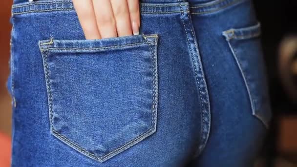 Kvinnlig hand klättrar i fickan på jeans på röven — Stockvideo