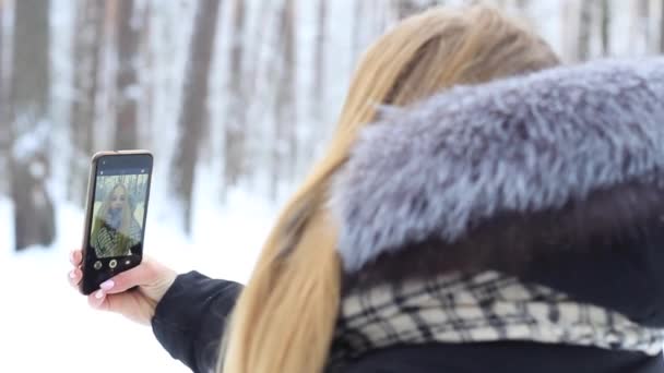 女孩在雪林与电话在反射欢欣鼓舞 — 图库视频影像