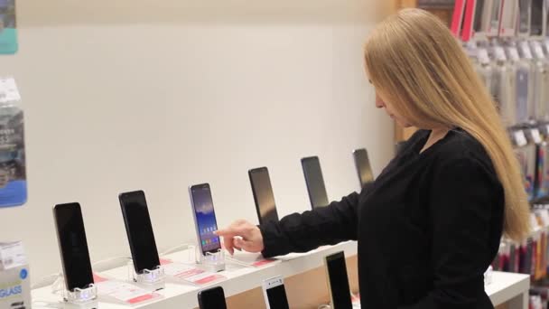 Het meisje overweegt een mobiel apparaat in de winkel — Stockvideo