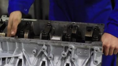 Bir adam araba motorunu tamir eder.