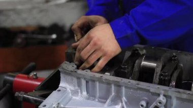 Bir adam araba motorunu tamir eder.