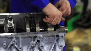 Bir adam araba motorunu tamir eder.