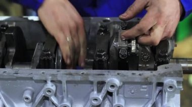 Bir adam araba motorunu tamir eder.