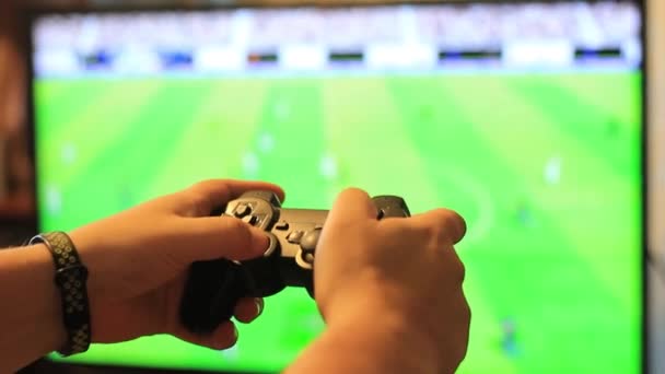 Il ragazzo tiene in mano un joystick da gioco e gioca a calcio. Schermo sfocato del monitor . — Video Stock