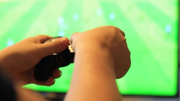 El tipo sostiene un joystick de juego en sus manos y juega al fútbol. Pantalla de monitor borrosa . — Vídeo de stock