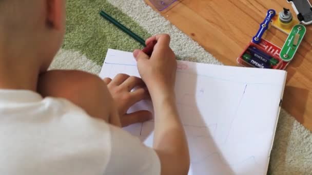 La mano de un niño dibuja en una hoja de papel . — Vídeos de Stock