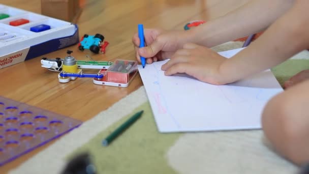 Die Hand eines kleinen Jungen zeichnet auf ein Blatt Papier. — Stockvideo