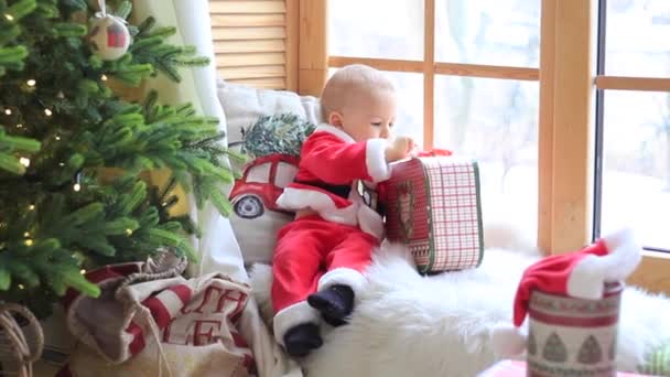 サンタ少年の小さな子供は、自宅でクリスマスを祝います。男の子かわいい子供陽気な気分クリスマスプレゼント — ストック動画