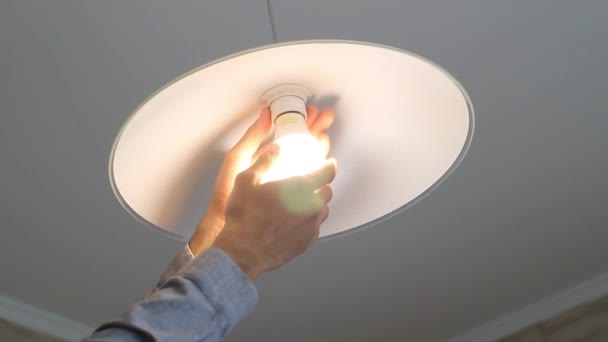 Рука чоловіка вкручує лампочку в люстру на кухні — стокове відео