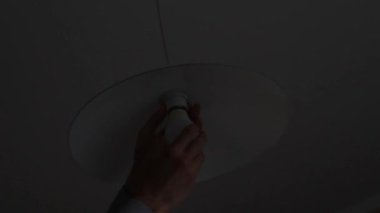 bir adam el mutfakta bir avize içine bir ampul vidalama