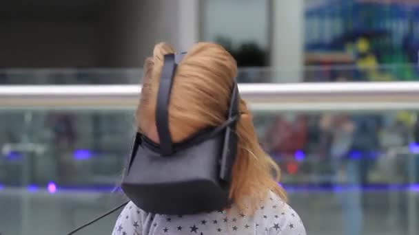 Ett barn med ett virtuellt Reality-headset. Flickan sitter i en stol med specialeffekter. — Stockvideo