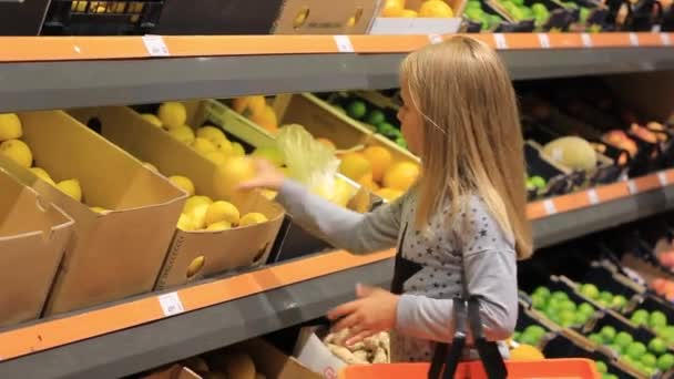 小さな女の子は食料品店でレモンを選ぶ — ストック動画