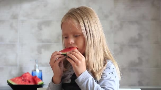 Klein meisje eet watermeloen in de keuken — Stockvideo