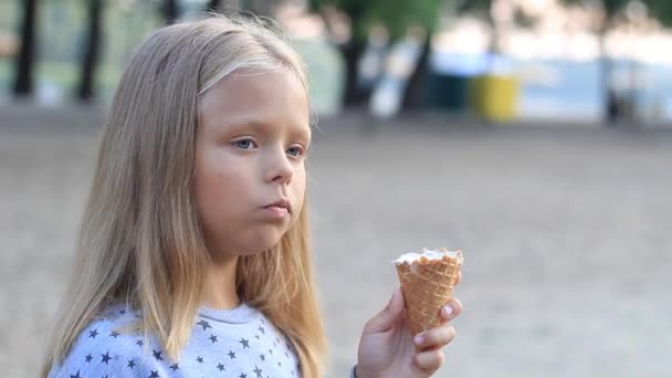 Little girl in the park eats ice cream cone close-up — Stock Video
