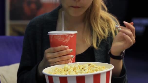 Mädchen isst Popcorn und trinkt ein Getränk — Stockvideo