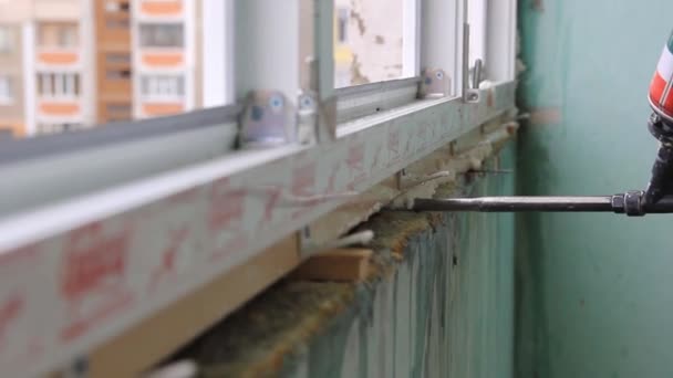 Arbeiter trägt Polyurethanschaum auf, um Lücke zwischen Flügel und Fensterrahmen zu füllen. — Stockvideo
