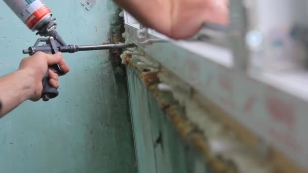 Trabajador está aplicando espuma de poliuretano para llenar el espacio entre el marco del marco y la ventana . — Vídeos de Stock