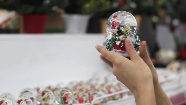 Руки женщины держат рождественскую игрушку и крутят её. — стоковое видео