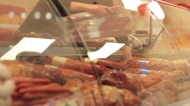 Primer plano de la mano de las carniceras mostrando salchichas en la tienda — Vídeos de Stock