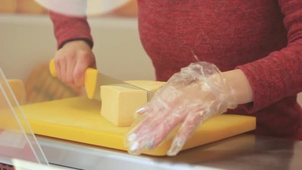 Mão feminina corta queijo com uma faca no tabuleiro — Vídeo de Stock