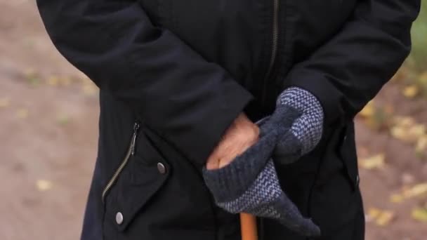 Old womans hand puts on gloves and holds a cane for emphasis close up. — Stock Video