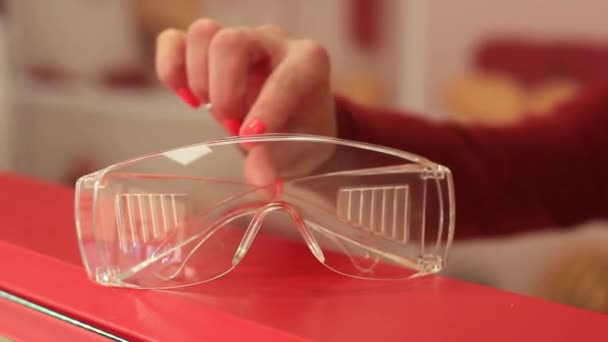 Жіноча рука бере пластикові прозорі окуляри, які захищають слизову оболонку від вірусу . — стокове відео
