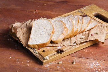 Taze ve güzel kokulu beyaz ekmek dilimlenmiş ve bir ahşap zemin üzerine yalancı. Biraz baharat kendisine eklenmiş ve aynı zamanda kraft kağıt üzerinde yatıyor. Gluten-Alerjik. Kavramsal gıda fotoğraf.