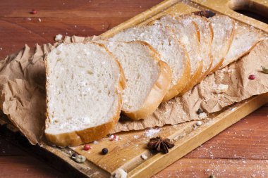 Taze ve güzel kokulu beyaz ekmek dilimlenmiş ve bir ahşap zemin üzerine yalancı. Biraz baharat kendisine eklenmiş ve aynı zamanda kraft kağıt üzerinde yatıyor. Gluten-Alerjik. Kavramsal gıda fotoğraf.
