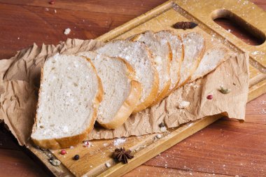 Taze ve güzel kokulu beyaz ekmek dilimlenmiş ve bir ahşap zemin üzerine yalancı. Biraz baharat kendisine eklenmiş ve aynı zamanda kraft kağıt üzerinde yatıyor. Gluten-Alerjik. Kavramsal gıda fotoğraf.