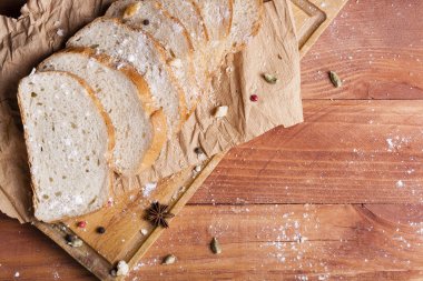 Taze ve güzel kokulu beyaz ekmek dilimlenmiş ve bir ahşap zemin üzerine yalancı. Biraz baharat kendisine eklenmiş ve aynı zamanda kraft kağıt üzerinde yatıyor. Gluten-Alerjik. Kavramsal gıda fotoğraf.