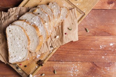 Taze ve güzel kokulu beyaz ekmek dilimlenmiş ve bir ahşap zemin üzerine yalancı. Biraz baharat kendisine eklenmiş ve aynı zamanda kraft kağıt üzerinde yatıyor. Gluten-Alerjik. Kavramsal gıda fotoğraf.