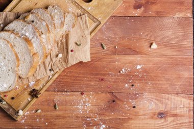 Taze ve güzel kokulu beyaz ekmek dilimlenmiş ve bir ahşap zemin üzerine yalancı. Biraz baharat kendisine eklenmiş ve aynı zamanda kraft kağıt üzerinde yatıyor. Gluten-Alerjik. Kavramsal gıda fotoğraf.