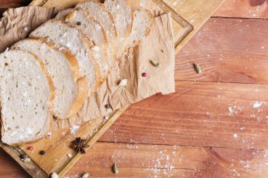 Taze ve güzel kokulu beyaz ekmek dilimlenmiş ve bir ahşap zemin üzerine yalancı. Biraz baharat kendisine eklenmiş ve aynı zamanda kraft kağıt üzerinde yatıyor. Gluten-Alerjik. Kavramsal gıda fotoğraf.