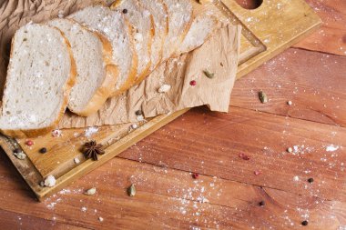 Taze ve güzel kokulu beyaz ekmek dilimlenmiş ve bir ahşap zemin üzerine yalancı. Biraz baharat kendisine eklenmiş ve aynı zamanda kraft kağıt üzerinde yatıyor. Gluten-Alerjik. Kavramsal gıda fotoğraf.